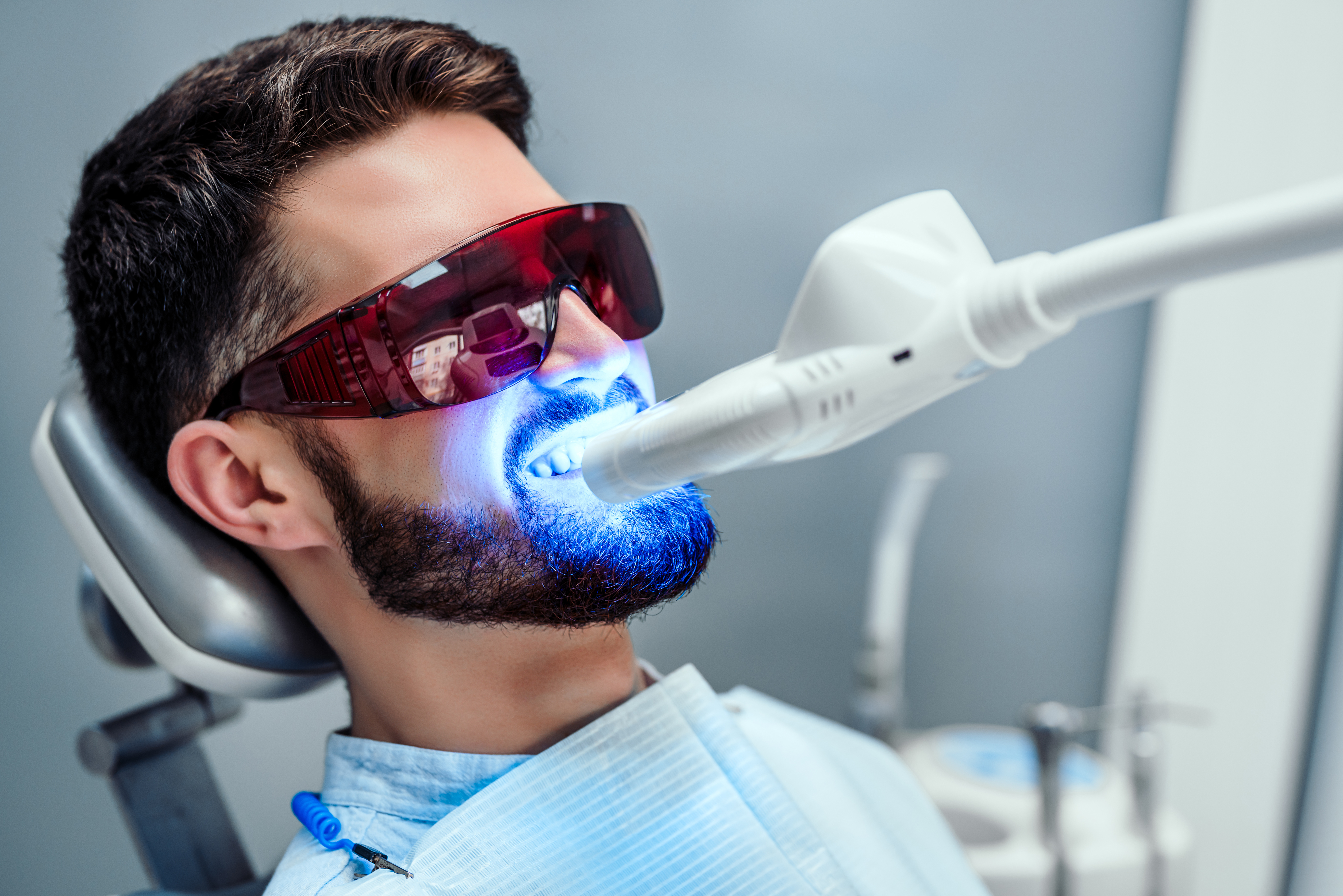 Close up view of man undergoing laser tooth whitening treatment to remove stains and discoloration. Close up view of man undergoing laser tooth whitening treatment to remove stains and discoloration.