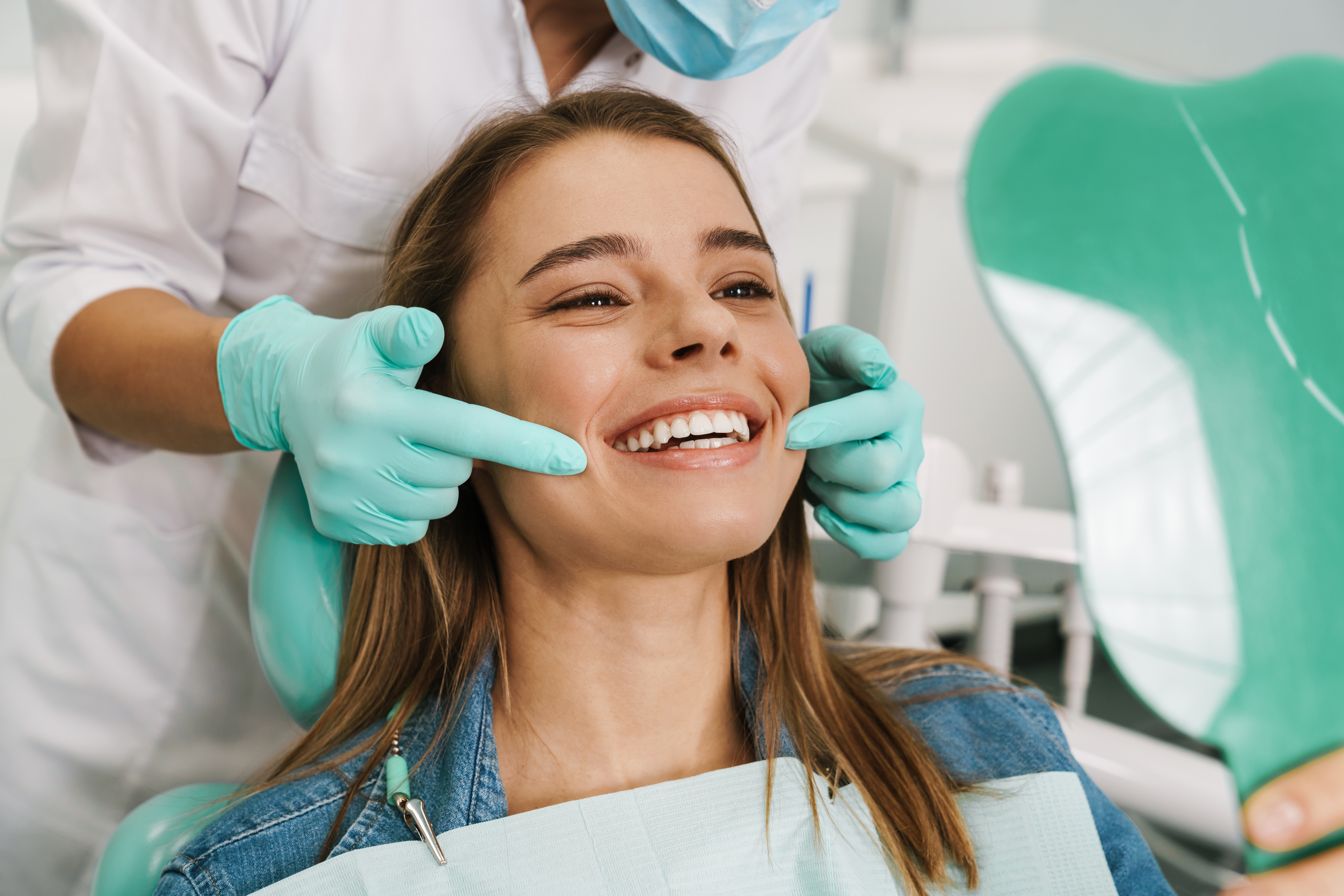 European young woman smiling while looking at mirror in dental c European young woman smiling while looking at mirror in dental clinic