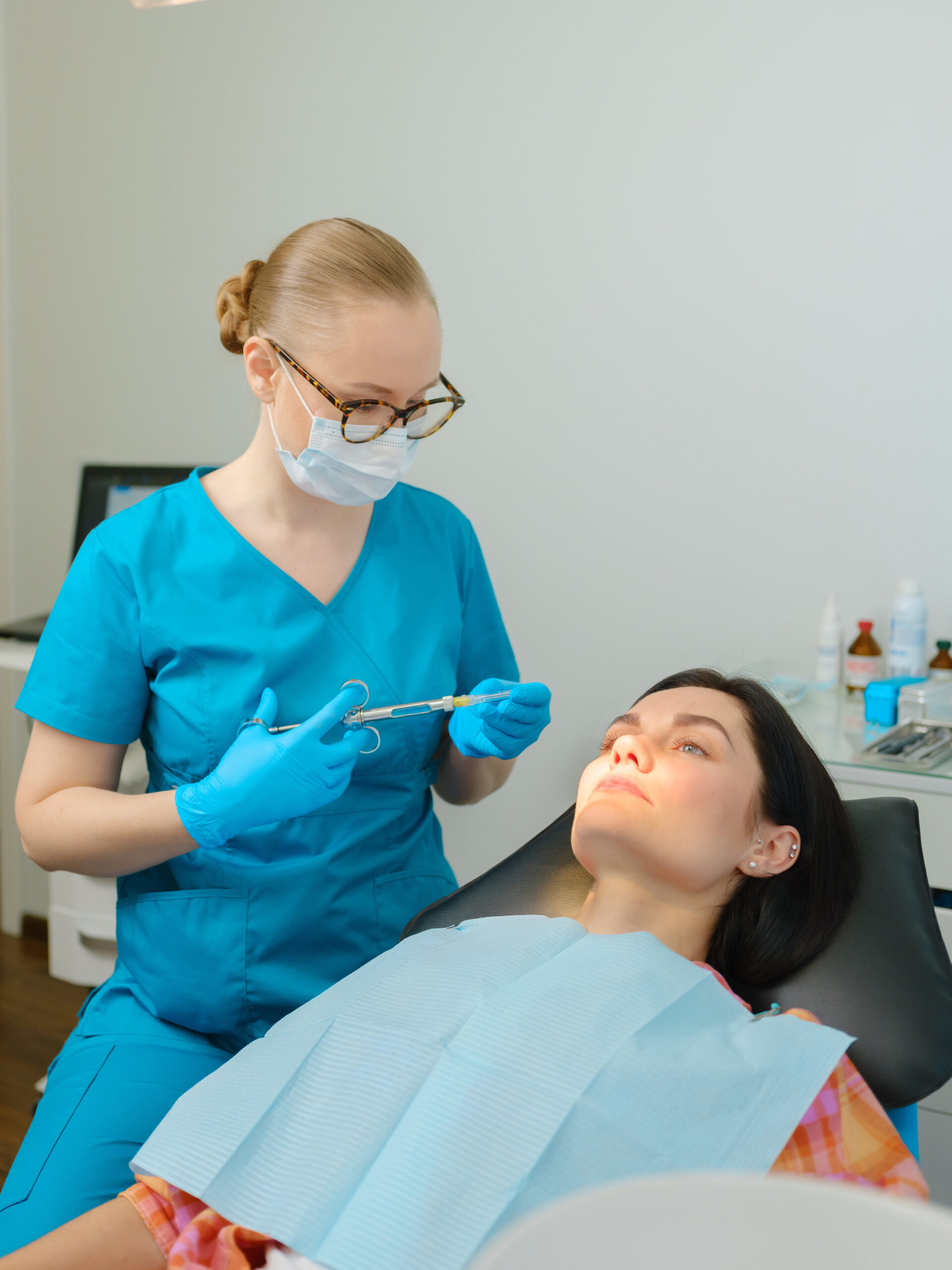 Female dentist with cartridge syringe getting ready to use anesthesia before teeth treatment Female dentist with cartridge syringe getting ready to use anesthesia before teeth treatment