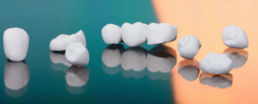 High aesthetic zirconia dentures and crowns on colorful background. Top view on set of single dentures and dental crowns.
