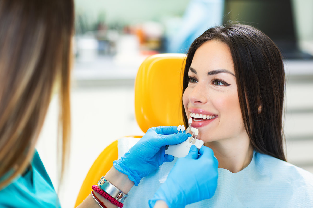 Dental patient Young beautiful women in dentist chair, check and select the color of the teeth.