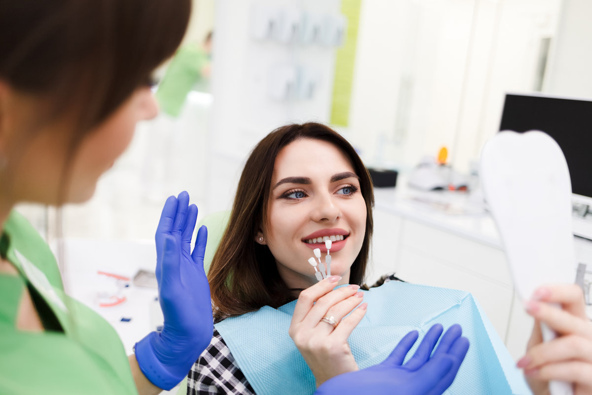 Girl chooses color of veneers at the dentist office Girl chooses color of veneers at the dentist office
