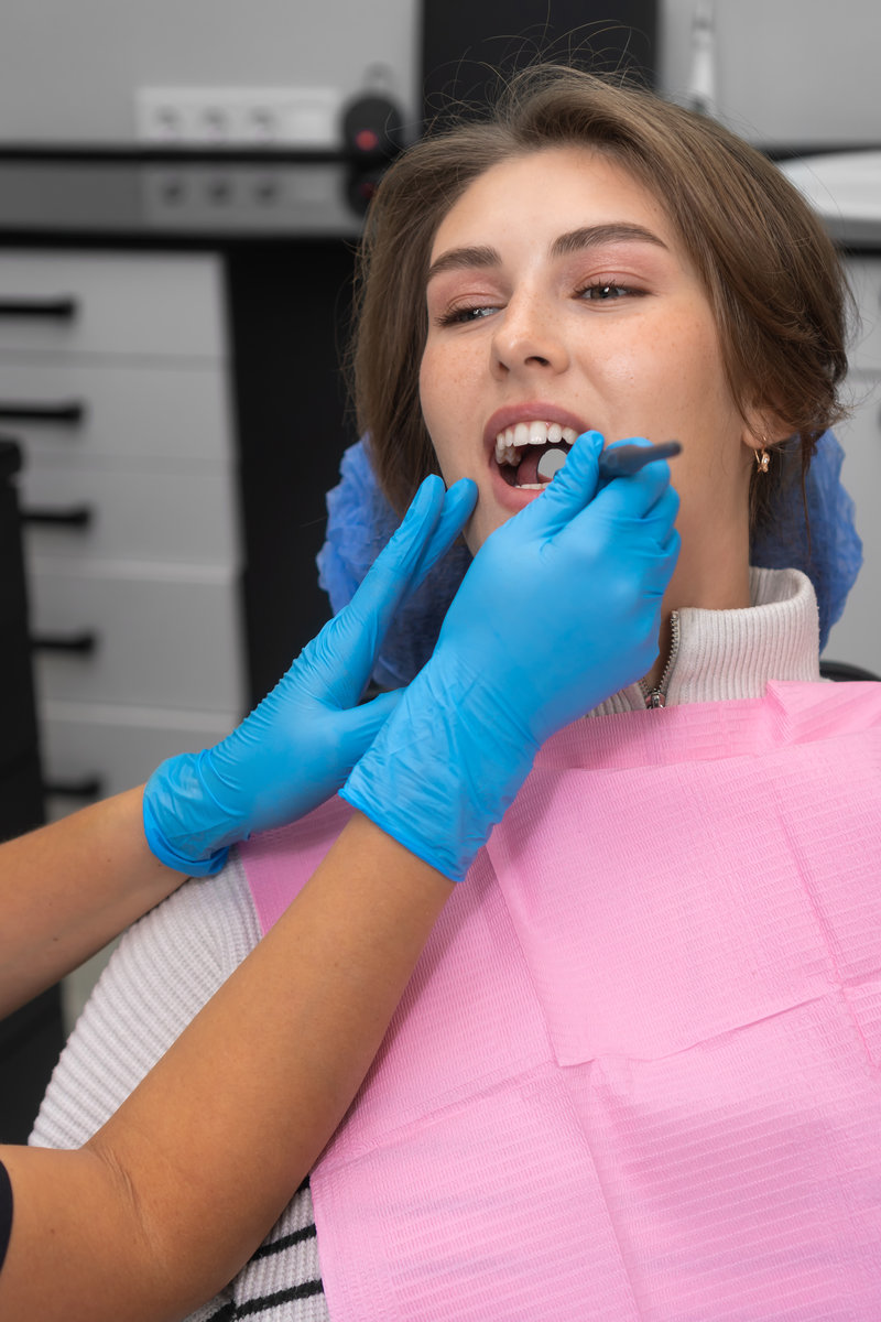 Close-up dentist examines the patient’s teeth using a dental mirror. Young beautiful woman at a dentist appointment. Concept of oral care. Vertical photo Close-up dentist examines the patient's teeth using a dental mirror. Young beautiful woman at a dentist appointment. Concept of oral care. Vertical photo