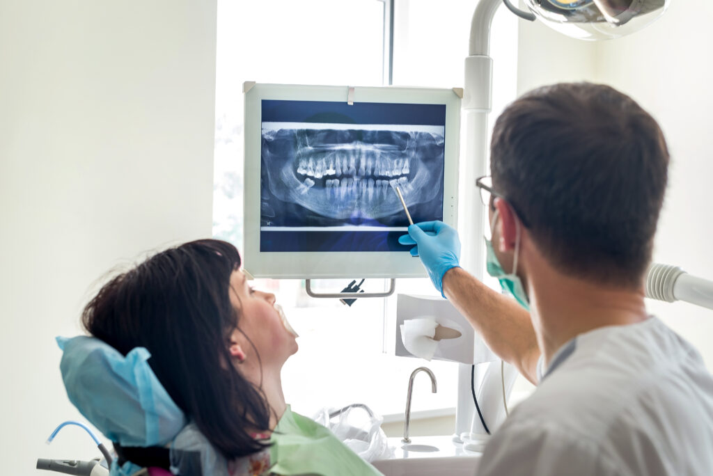 Dentist reviewing a dental X-ray on a monitor with a patient