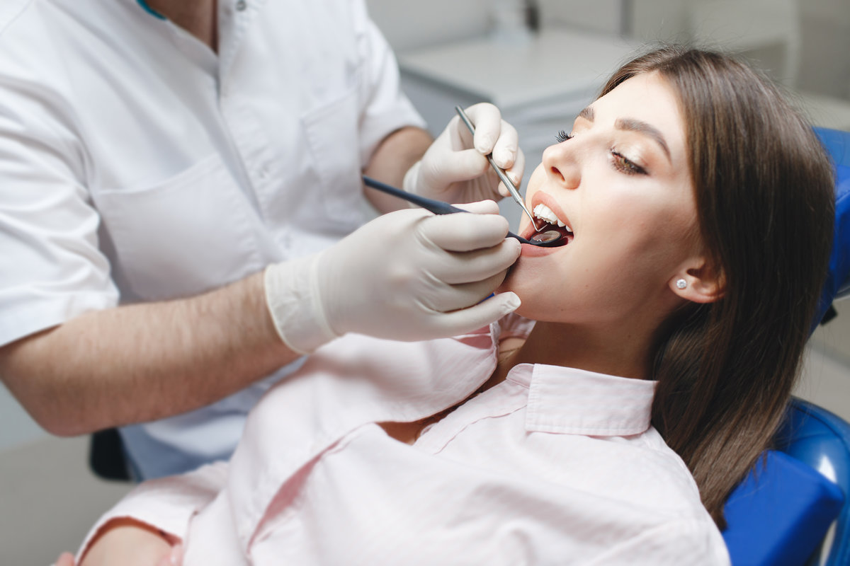 Dental clinic. Reception, examination of the patient. Teeth care. Young woman undergoes a dental examination by a dentist.Happy patient and dentist concept.Female dentist in dental office talking with Dr. Brittany Wood performing dental exam at Shoreline Dentistry Virginia Beach