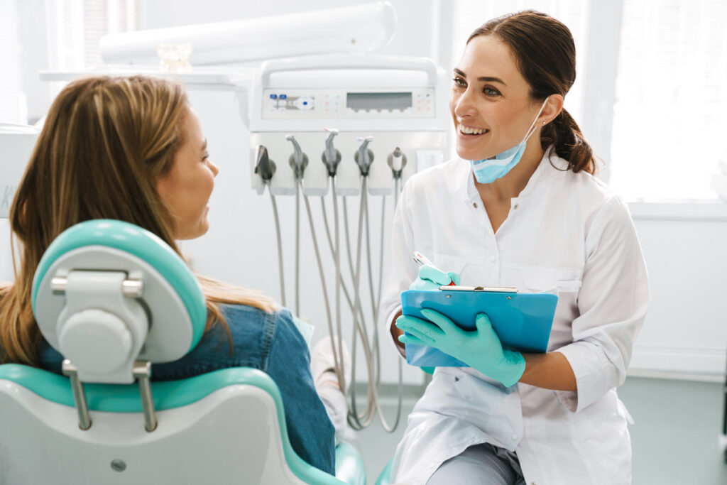 European mid dentist woman smiling while working with patient