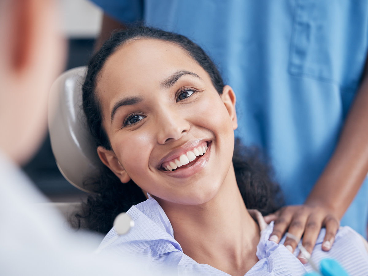 Dentist, healthcare and woman with a smile, checkup and teeth with oral hygiene, treatment and cleaning gum bacteria. Female person, patient and lady with dental care, prevent tooth decay and disease family smiling after preventive dentistry appointment at Shoreline Dentistry Virginia Beach